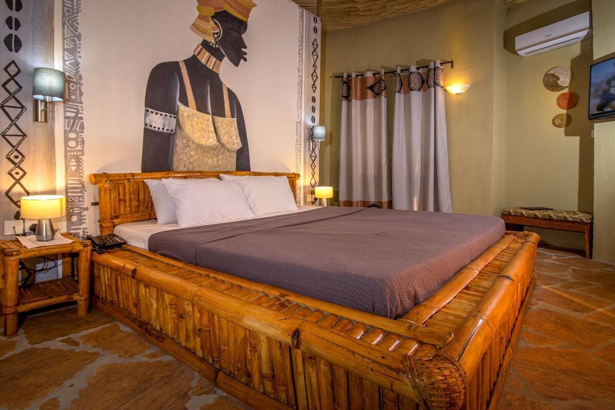 A room with a wooden bed, a wall mural, and a television.