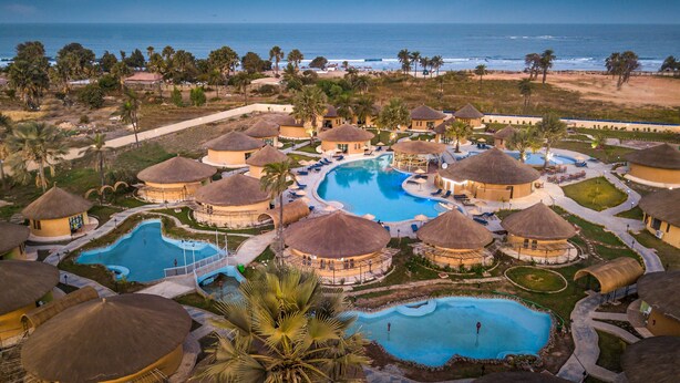 A resort with multiple pools, thatched-roof huts, and a beach view. - Bamboo Village Resort (Serrekunda)