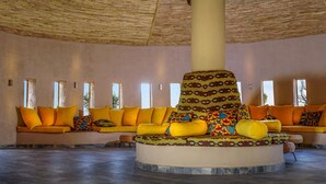 A circular seating area with a central pillar, surrounded by sofas with orange cushions. - Bamboo Village Resort (Serrekunda)
