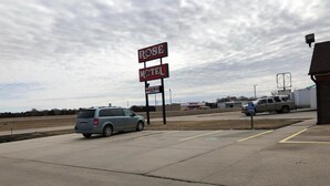 A Rose Motel sign, a parking lot, and a building in the background. - Rose Motel (David City)