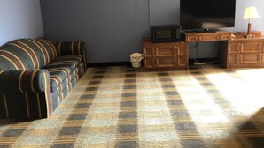 A living room with a sofa, a television, a microwave, and a wooden cabinet. - Rose Motel (David City)