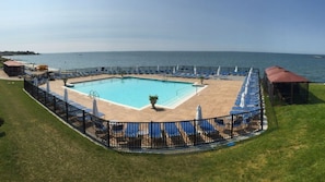 Une piscine rectangulaire entourée d’une terrasse, de chaises longues et de parasols.