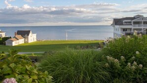 A coastal property with a large house featuring a balcony overlooking the sea.