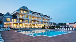 A multi-story hotel with a swimming pool and sun loungers.