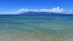 A clear view of a beach with shallow water and a mountain in the background.