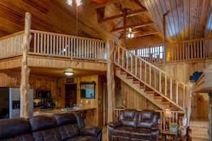 Eine geräumige Holzdiele mit Essbereich, Küche und einer Treppe, die zwei Ebenen verbindet.