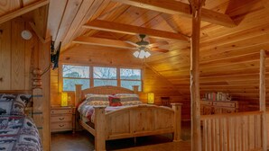 A wooden cabin bedroom with a bed, nightstands, a ceiling fan, and a window. - Secluded Log Cabin, Mountain Top, Hot Tub, Pool Table, 5 Miles From Downtown (Hot Springs)
