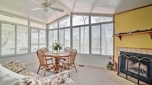 A sunlit room with a dining table, chairs, a sofa, a fireplace, and large windows. - Fishing Paradise w/ Deck On Suwannee River (Branford)