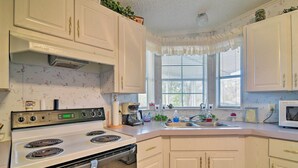 A kitchen with white cabinets, a stove, a microwave, and a window with blinds. - Fishing Paradise w/ Deck On Suwannee River (Branford)