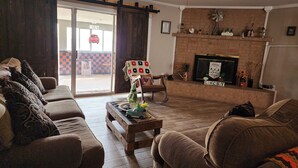Un salon avec deux canapés, une table basse et une cheminée. Une porte coulissante donne accès à un espace extérieur doté d’un sol à carreaux.
