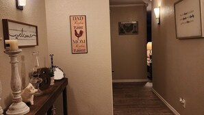 Un couloir doté d’un plancher en bois, d’une console ornée d’objets décoratifs et d’appliques murales.