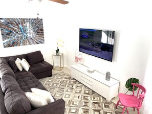 A living room with a sectional sofa, a flat-screen TV, a coffee table, and a decorative plant. - Two Bedroom Apartment, Pool -2 Min Walk to Miami Design District (Miami)