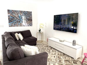 A modern living room with a sectional sofa, a white console table, and a large flat-screen TV mounted on the wall. - Two Bedroom Apartment, Pool -2 Min Walk to Miami Design District (Miami)