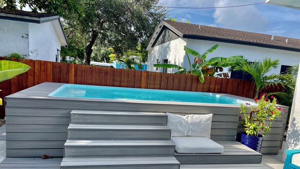 A backyard with a swimming pool, wooden deck, and steps leading to a seating area with a white cushion. - Two Bedroom Apartment, Pool -2 Min  Walk to Miami Design District (Miami)