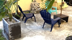 An outdoor seating area with two blue chairs and a small table, surrounded by potted plants and a yellow wall. - Two Bedroom Apartment, Pool -2 Min  Walk to Miami Design District (Miami)