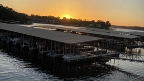 A marina with docked boats and a large building in the background during sunset. - Ledges 3BR 2BA, Ground Floor, Water Front, 10x30 slip, 2 Pools and Beach. (Osage Beach)