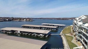 A waterfront hotel with multiple dock areas and a modern building structure. - Ledges 3BR 2BA, Ground Floor, Water Front, 10x30 slip, 2 Pools and Beach. (Osage Beach)