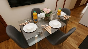 A dining table set with plates, glasses, cutlery, and a vase with flowers.
