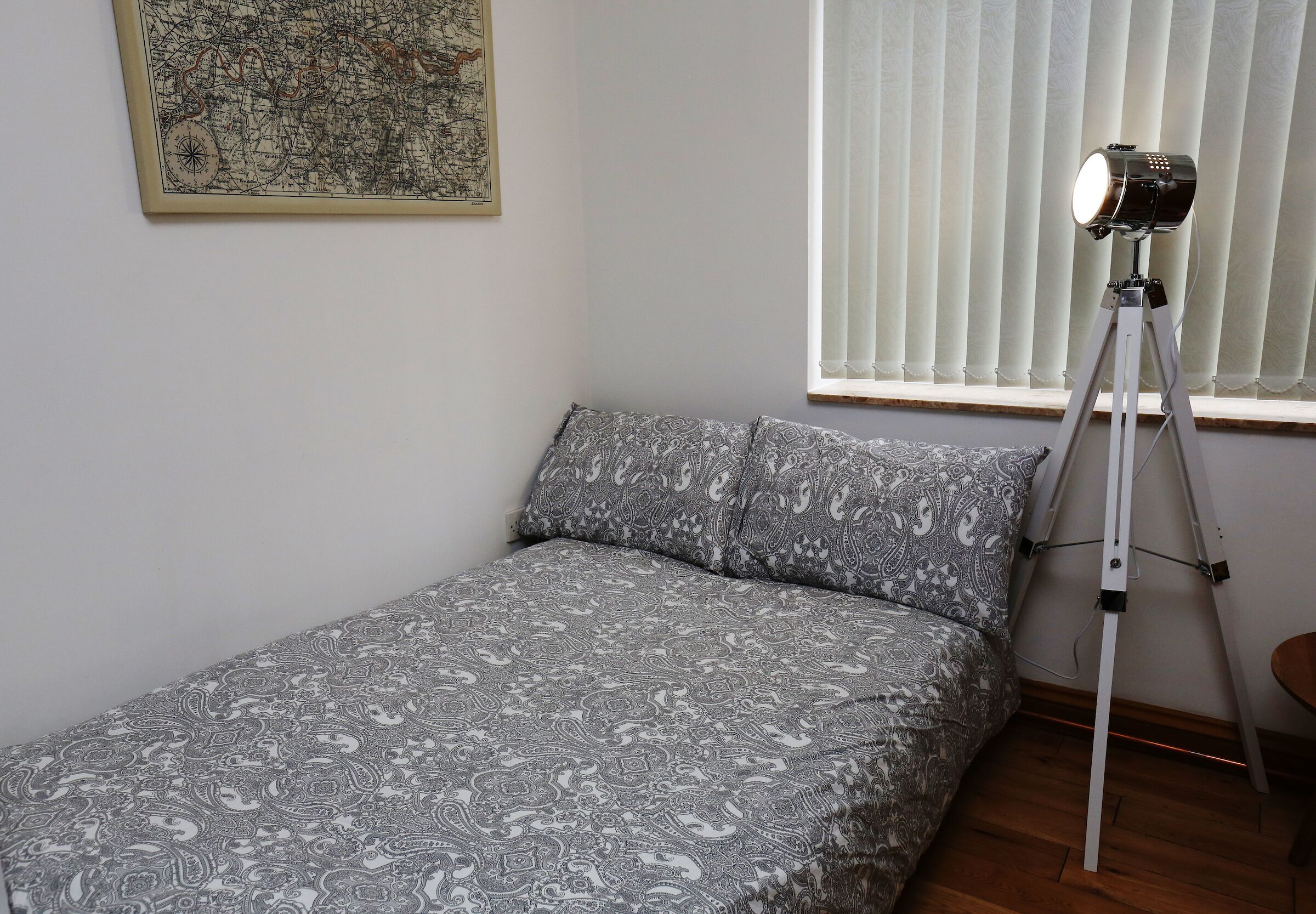 A small bedroom with a bed, a map on the wall, and a telescope by the window.