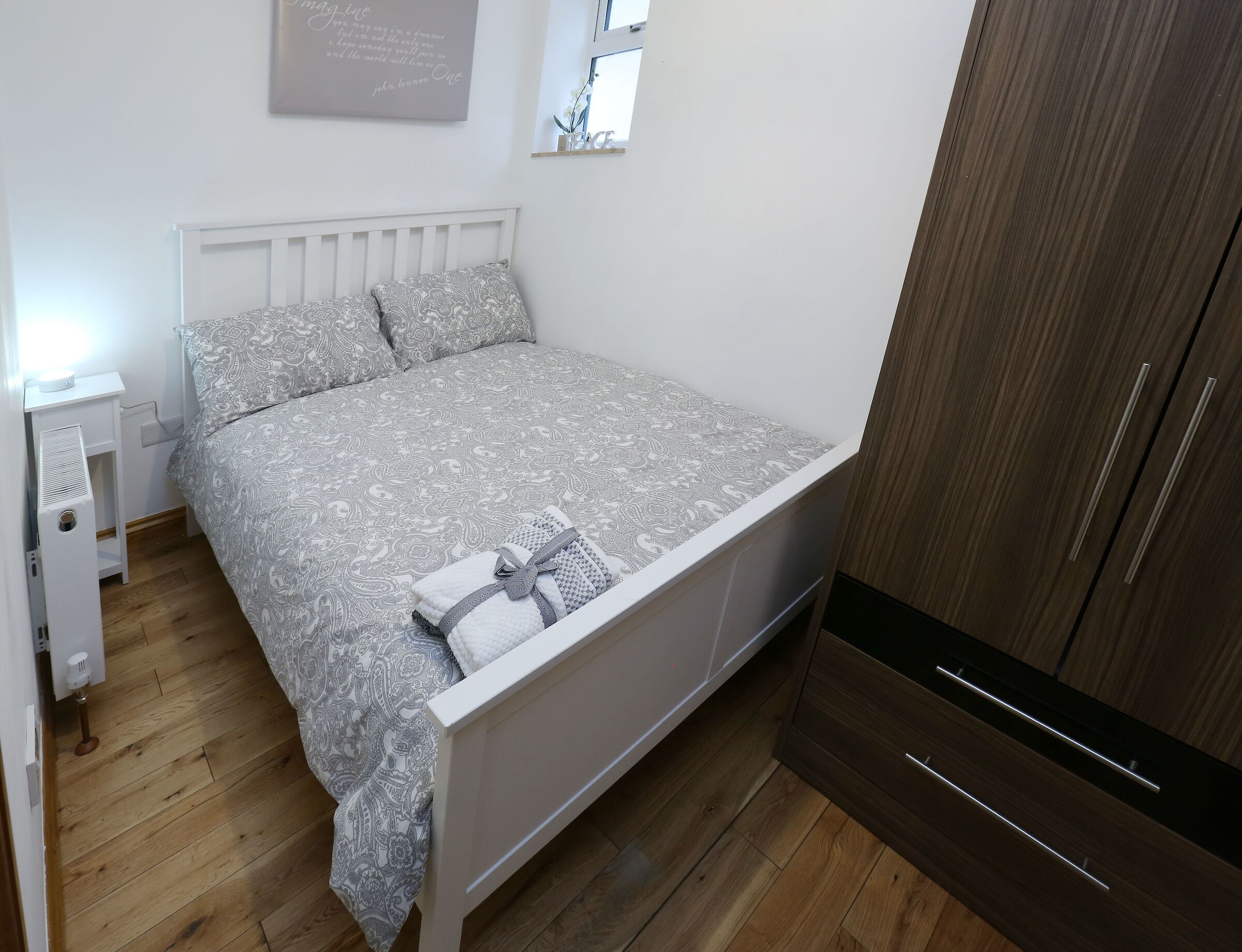 Une chambre à coucher avec un lit, une table de chevet et une armoire.