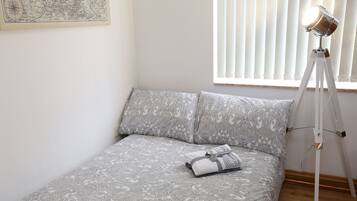 A neatly made bed with patterned bedding, a bedside lamp, and a map on the wall.