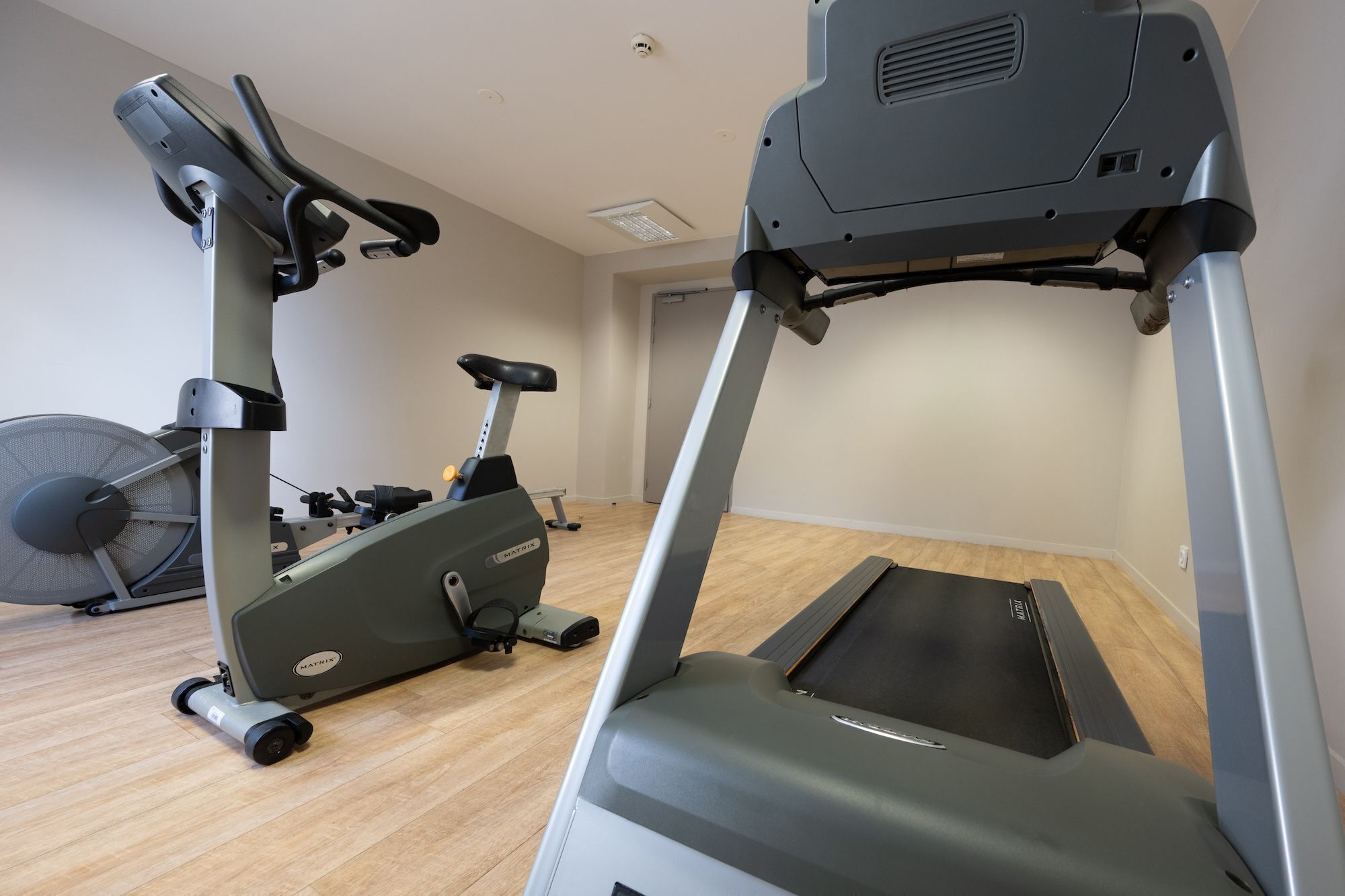A gym with two treadmills, a stationary bike, and a fan.