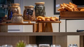 Een presentatie van diverse etenswaren, waaronder potjes met zaden en een houten schaal met gebak.