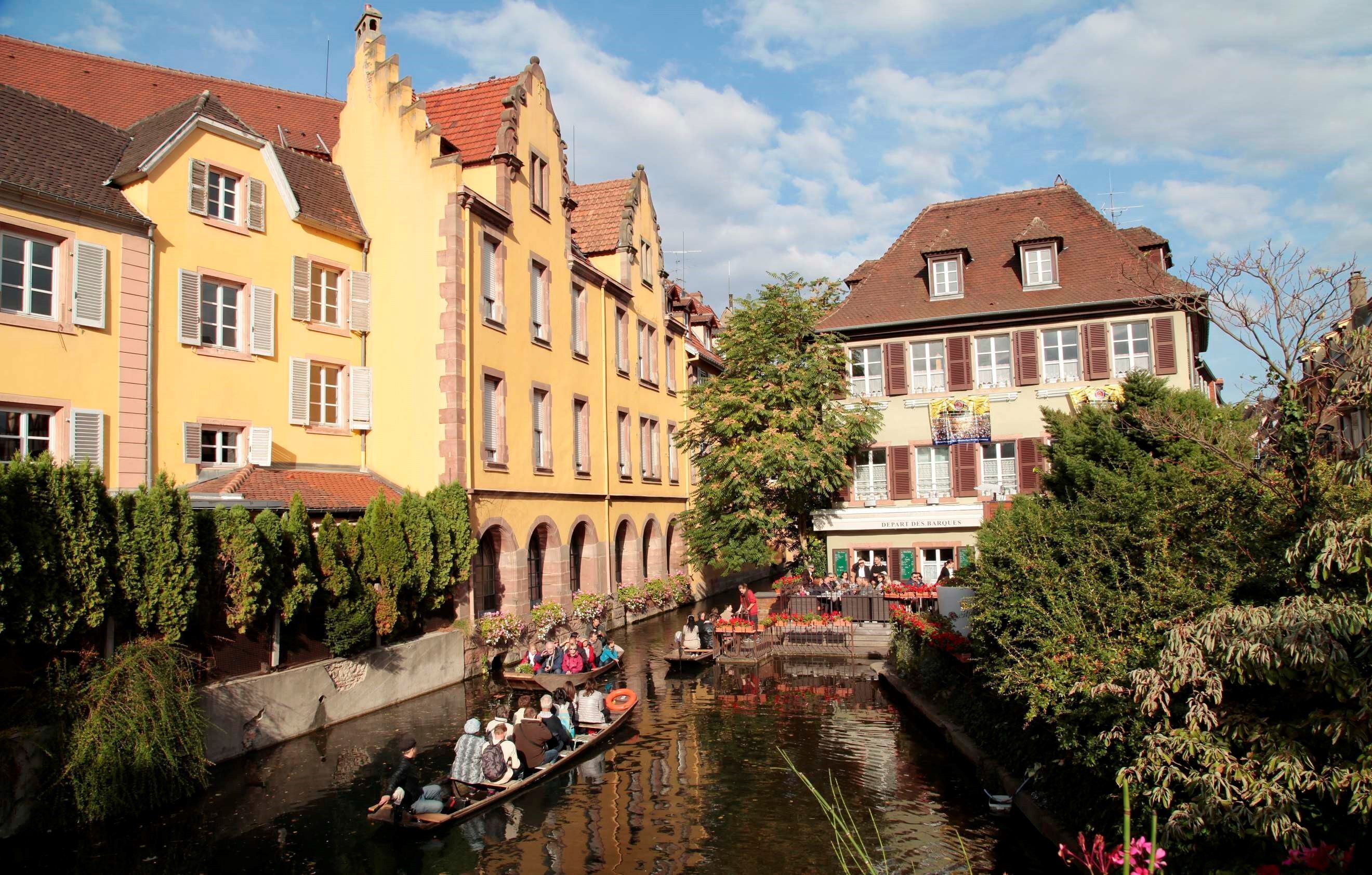 Um canal com barcos, cercado por edifícios históricos com telhados de terracota e persianas.