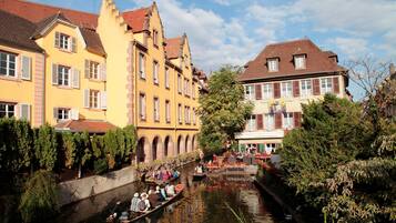 Um canal com barcos, cercado por edifícios históricos com telhados de terracota e persianas.