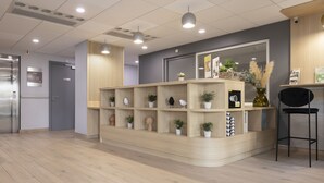 A reception area with a wooden reception desk, potted plants, and a black chair.