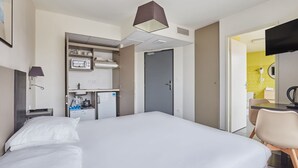 A hotel room with a bed, a desk, a kitchenette, and a TV. - Studio Spacieux | 200m de L'Avenue du Prado (Marseille)