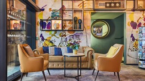 A cozy lounge area with a sofa, two armchairs, a small round table, and a mirror.