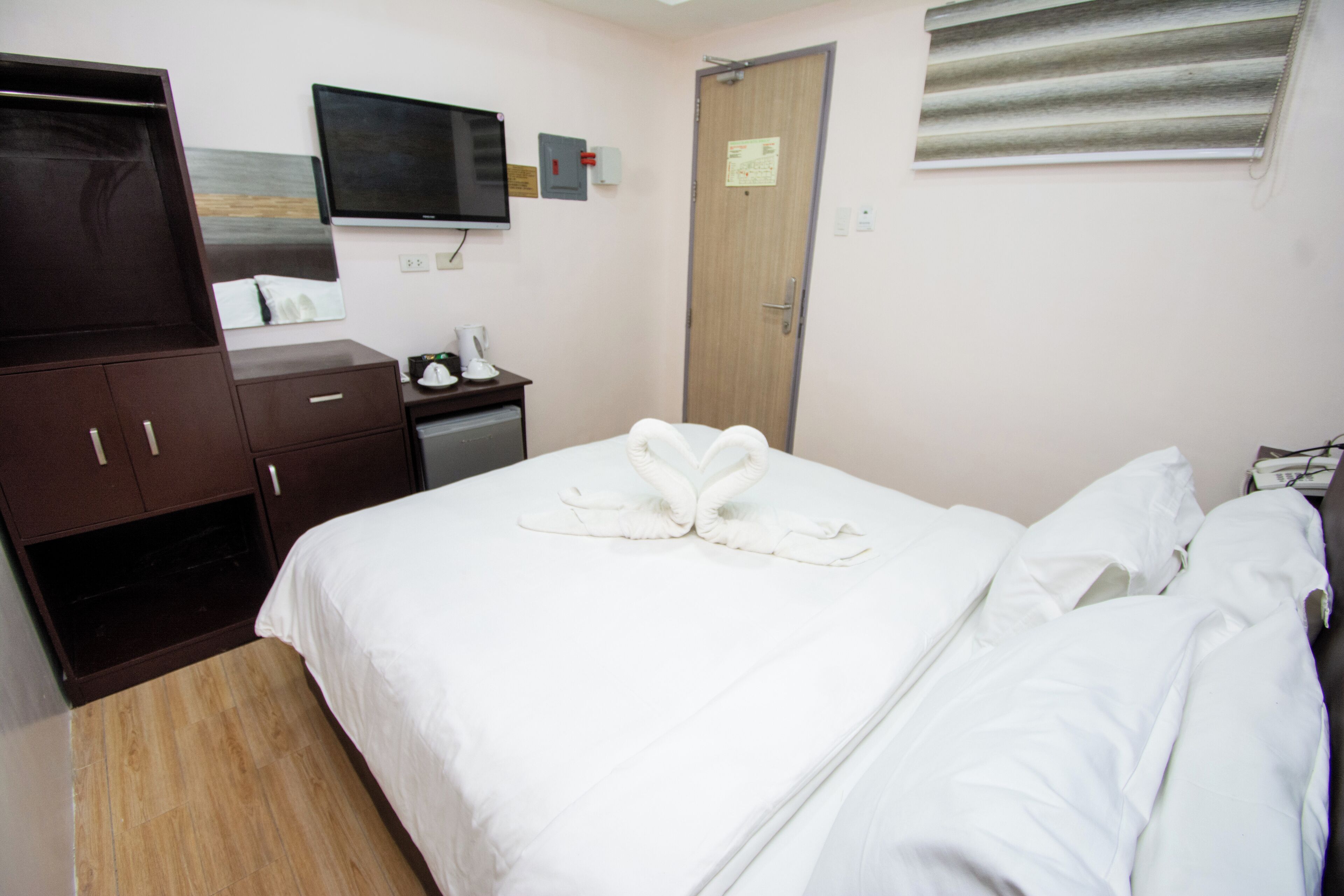 Ein Hotelzimmer mit Bett, Schreibtisch, Fernseher und Kleiderschrank.