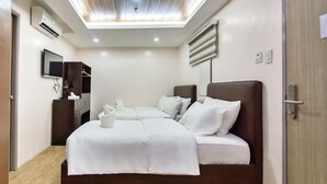 A modern hotel room with a large bed, a flat-screen TV, and a ceiling light fixture.