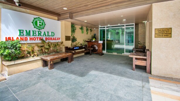 The interior of Emerald Island Hotel Boracay with a reception area featuring a wooden bench, a reception desk, and a sign indicating guest-only access.