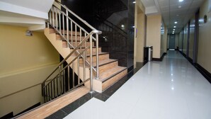 A modern interior with a staircase, a trash bin, and a hallway.