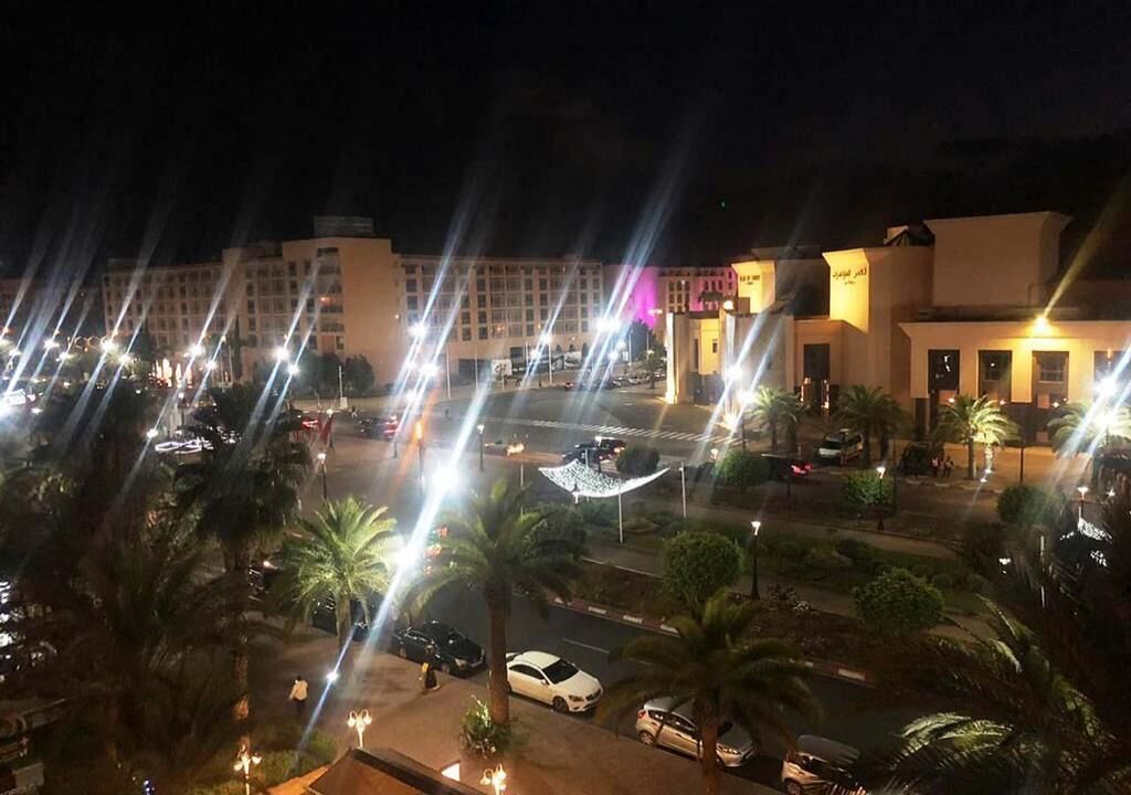 Un hôtel à plusieurs étages, doté d’un parking et bordé de palmiers.