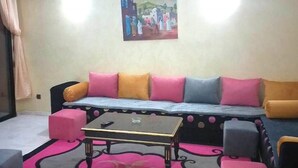 A living room with a sofa, ottomans, a coffee table, and a painting on the wall. - Residence Atlas Marrakech 4700 (Marrakech)