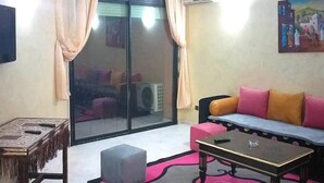 A living room with a sofa, a coffee table, a small table, and a sliding glass door leading to a balcony. - Residence Atlas Marrakech 4700 (Marrakech)