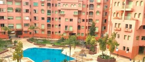 A multi-story hotel with a swimming pool area, including two pools and surrounding greenery.