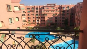 Un edificio de varios pisos con balcones, piscina y cielo despejado.