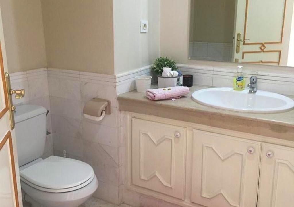 Une salle de bain avec des toilettes, un lavabo et un miroir.
