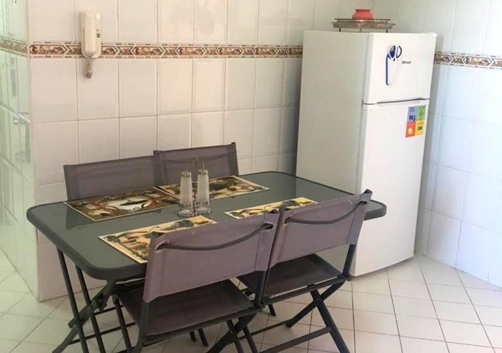 Une cuisine compacte comprenant une table à manger, des chaises, un réfrigérateur et un crédence décorative.