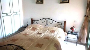 A bedroom with a bed, a nightstand, a lamp, and two framed pictures on the wall. - Residence Atlas Marrakech 4680 (Marrakech)