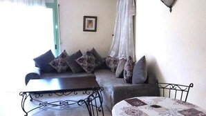 A cozy living area with a sofa, a small table, and a bed. - Residence Atlas Marrakech 4680 (Marrakech)