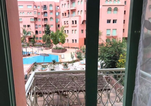 A view of a pink building with a pool and landscaped garden.