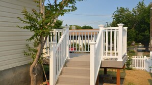 A wooden deck with white railings leading to a house.