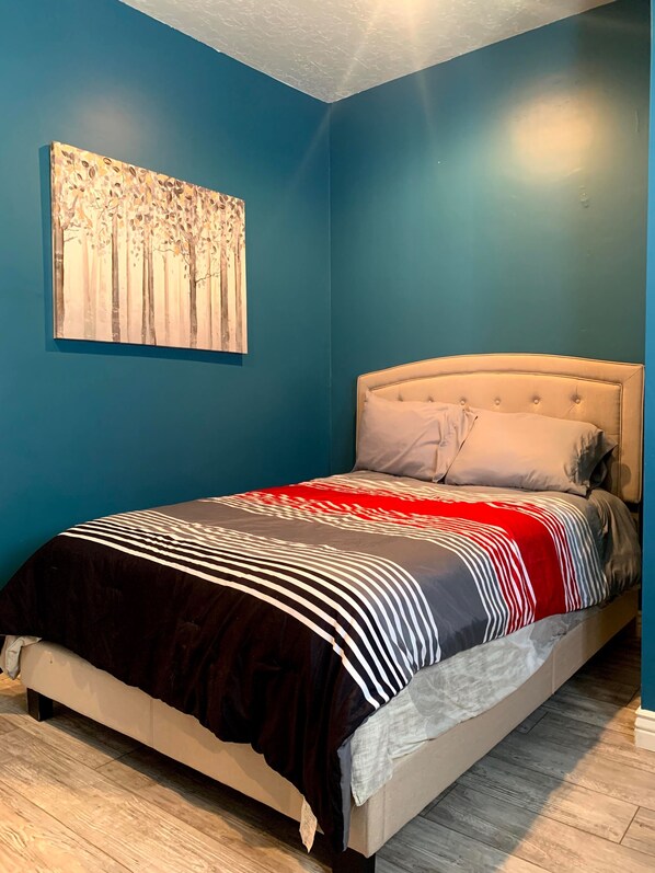Un dormitorio con una cama, un cuadro en la pared y una pared azul.