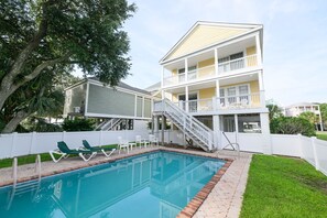 Une maison à deux étages avec une piscine, un patio couvert et une clôture blanche.