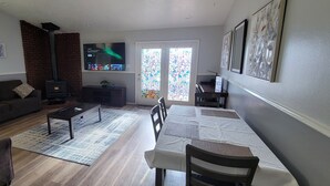 A living room with a sofa, coffee table, and a TV. There is a fireplace, a dining table with chairs, and a window with a view. -  Entire Townhouse 1 Car Garage +Jacuzzi (West Wendover)